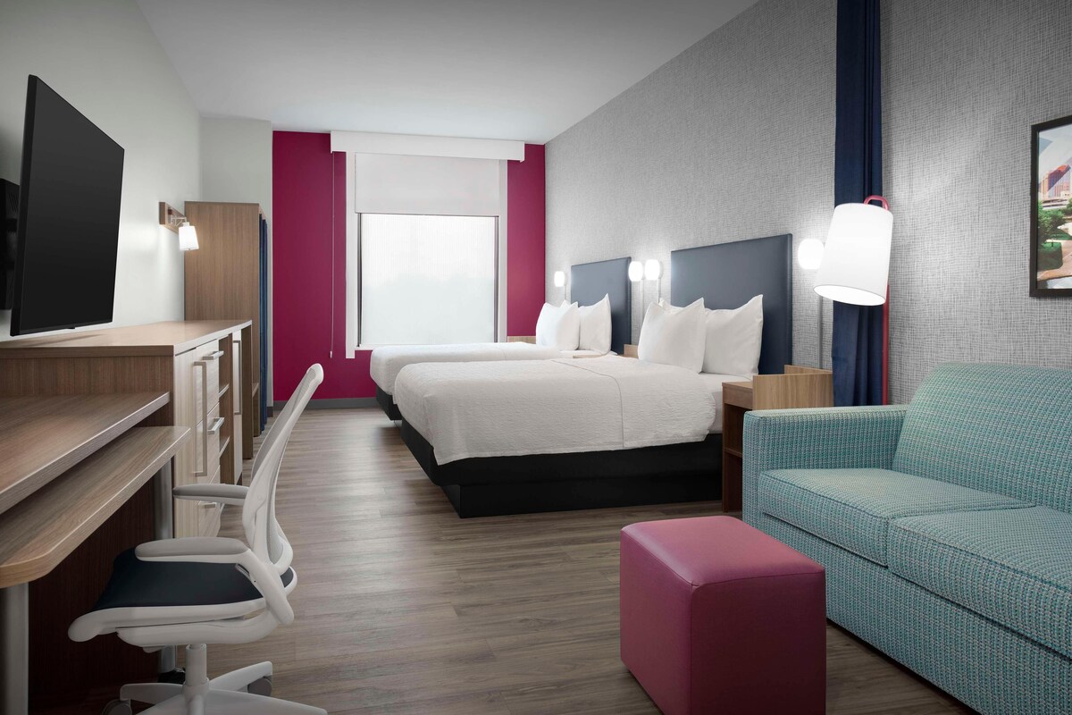 Una habitación de hotel con cama, escritorio, silla, sofá y televisor.