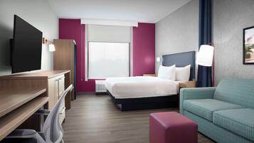 A modern hotel room with a bed, a desk, a chair, a sofa, and a TV.