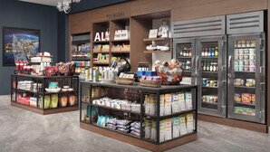 Una tienda con estantes llenos de aperitivos, bebidas y artículos de viaje.