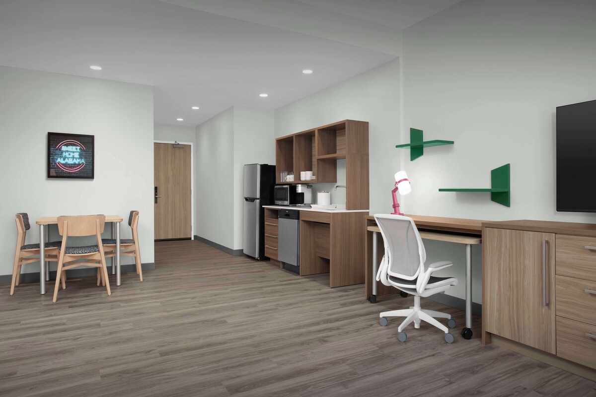 A modern office space with a wooden desk, white office chair, and a dining table with chairs.