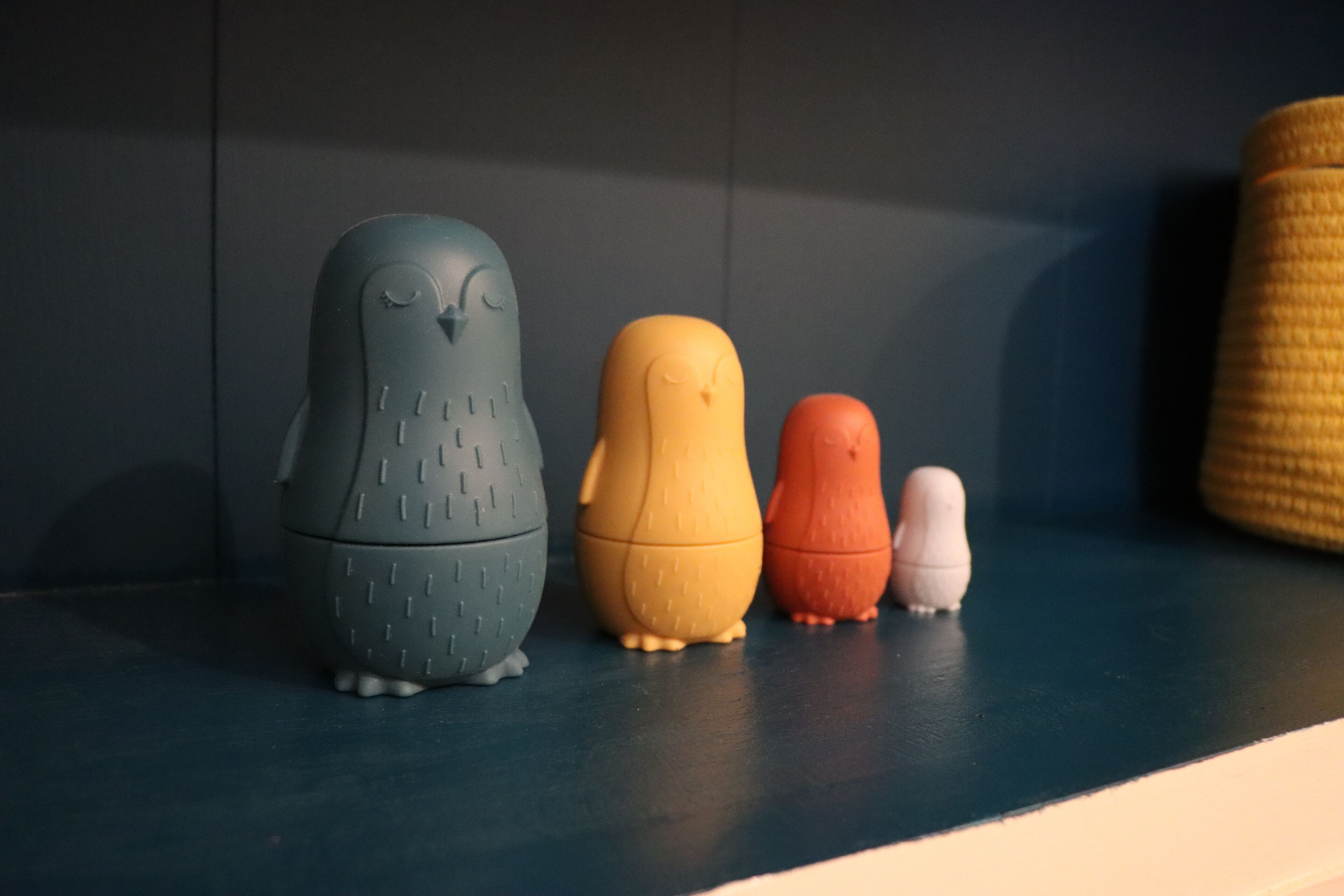 A shelf with three owl-shaped objects in different colors.