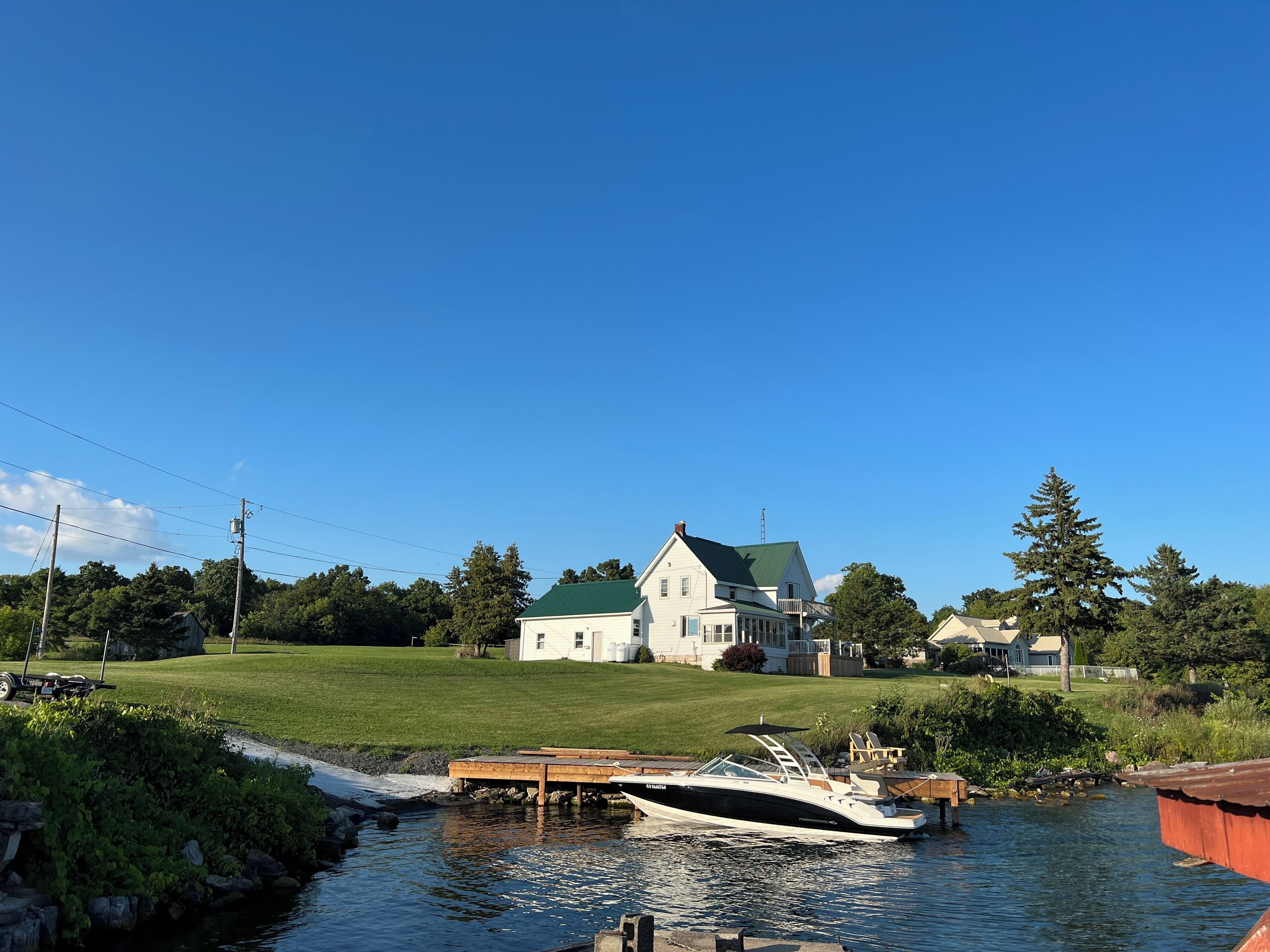 A house with a green roof, a dock, and a boat.