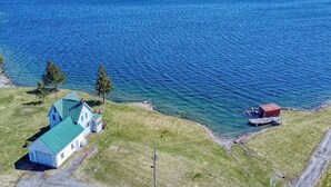 Une propriété située sur la côte, comprenant une grande maison, un quai et un petit abri au bord de l’eau.