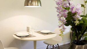 Un coin repas avec une table ronde, des chaises blanches et un luminaire suspendu.