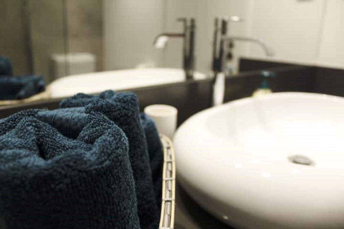 Un baño con lavamanos blanco, una toalla y un espejo.