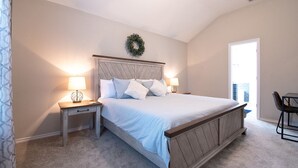 A bedroom with a bed, two bedside tables with lamps, a chair, a door, and a window. - Texas Roots: King Beds - 6 Minutes to Downtown McKinney- Sleeps 6 - Remodeled (McKinney)