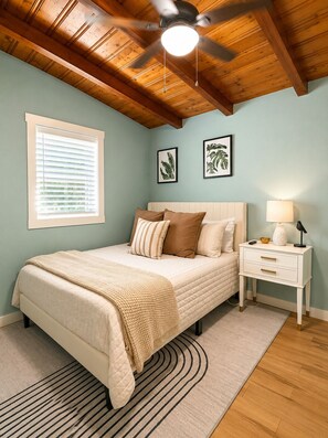A bedroom with a bed, a nightstand, a ceiling fan, and a window with blinds.