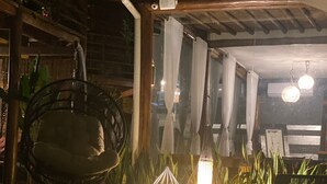 Eine Terrasse aus Holz mit einer Hängematte, Topfpflanzen und einem Tisch mit Lampe.