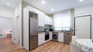 A compact kitchen with a refrigerator, microwave, oven, washing machine, and dishwasher. - GuestReady – Enjoy Madrid in comfort and style (Madrid)