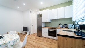 A compact kitchen with white cabinets, a stainless steel refrigerator, a built-in oven, and a wooden countertop. - GuestReady – Enjoy Madrid in comfort and style (Madrid)