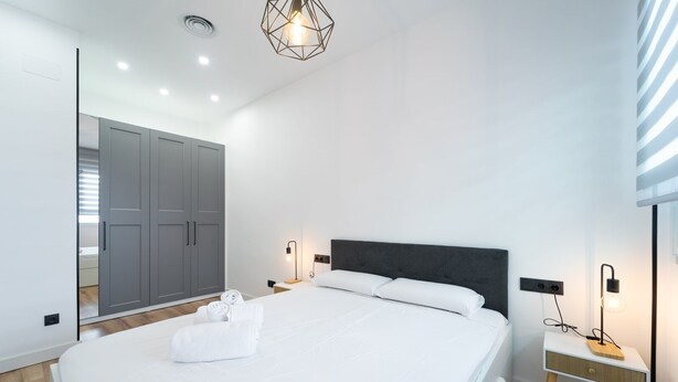 A modern bedroom with a large bed, grey wardrobe, and bedside tables with lamps. - GuestReady – Enjoy Madrid in comfort and style (Madrid)