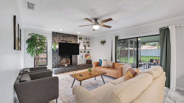 Una sala de estar con chimenea, ventilador de techo, sofá y mesa de centro.