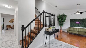 Un interior moderno con una escalera, un sofá verde y un adorno en la pared.