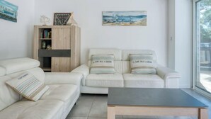 Un salon moderne avec un canapé blanc, un meuble en bois et un tableau accroché au mur.