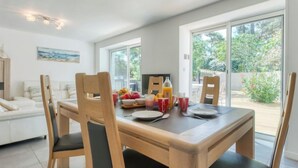Un coin repas avec une table en bois, quatre chaises et une vue sur l’extérieur grâce à de grandes fenêtres.