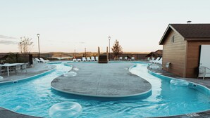 Una piscina con sillones de descanso y un edificio de madera.