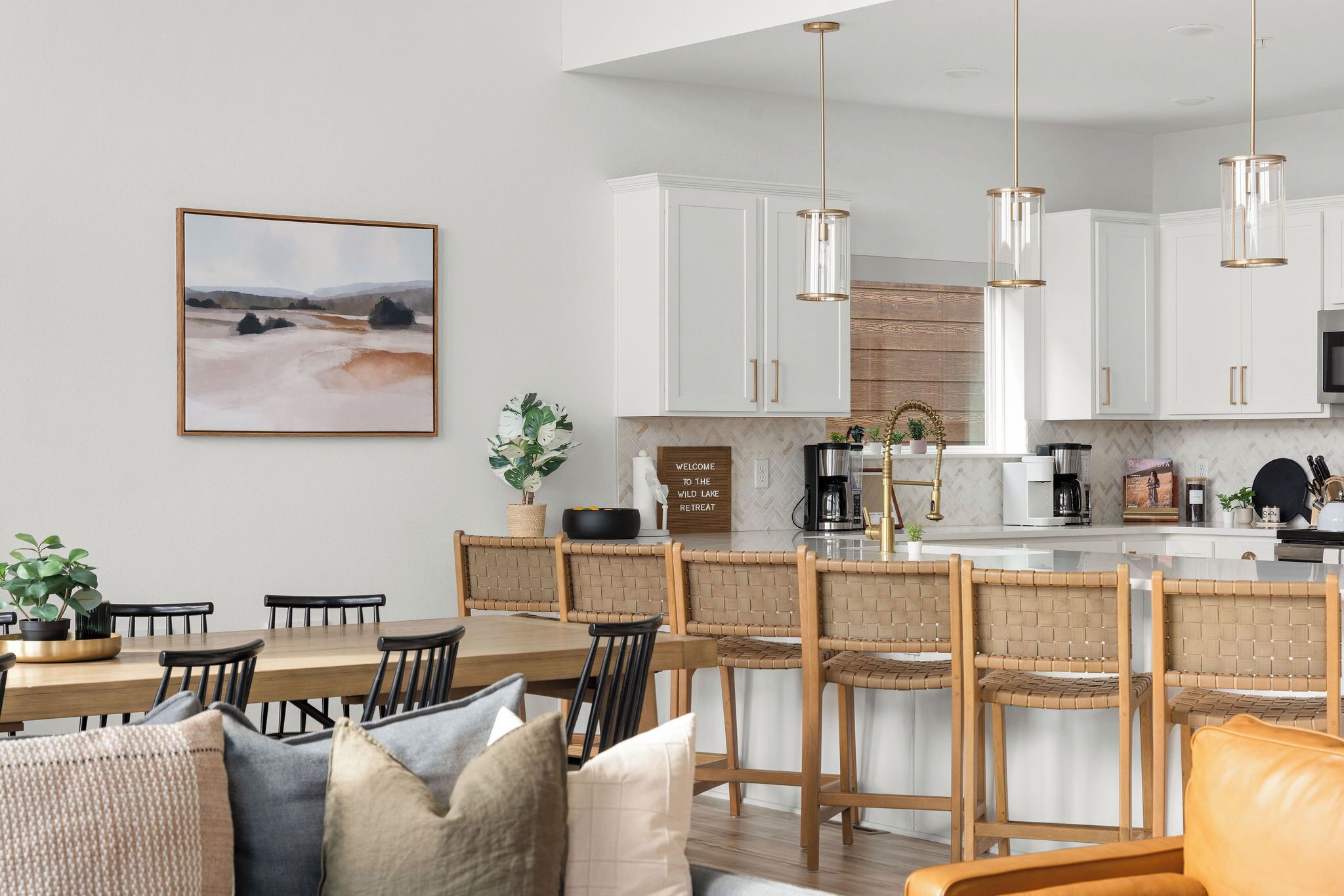 A modern kitchen with white cabinets, a central island, and hanging pendant lights.