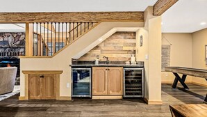 Un vaste espace de vie agrémenté d’un escalier en bois, d’une cuisine intégrée et d’une cheminée en pierre.