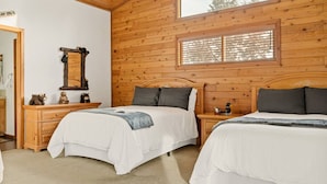 Una habitación con paneles de madera, dos camas, un tocador, un espejo y una ventana.
