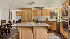 A modern kitchen with wooden cabinets, a central island, a built-in stove, and a large refrigerator. - Double Black Diamond | Bear Mtn w/ Hot Tub (Big Bear Lake)