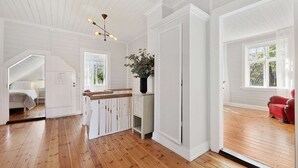Ein geräumiges Zimmer mit Holzböden, einer weißen Tür und einem roten Sessel.