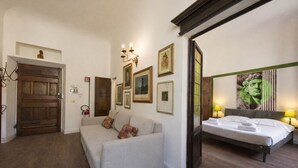 A room with a wooden door, a sofa, a bed, and framed pictures on the wall. - Ognissanti Flat in Florence by Mmega (Firenze)