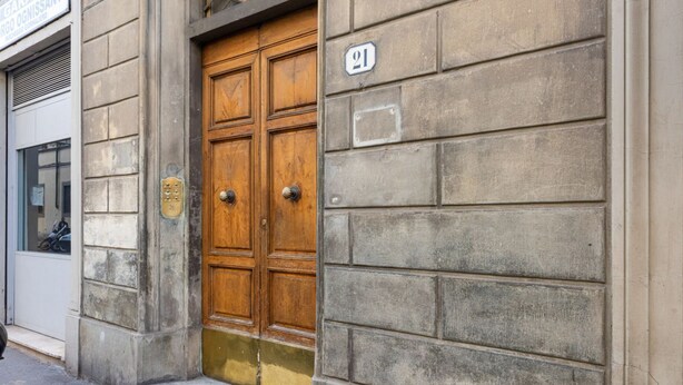 A building with a wooden double door, a stone facade, and a number plaque. - Ognissanti Flat in Florence by Mmega (Firenze)