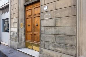 A building with a wooden double door, a stone facade, and a number plaque. - Ognissanti Flat in Florence by Mmega (Firenze)