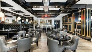 Un ristorante moderno con un bancone centrale, tavoli rotondi e sedie grigie rivestite in tessuto.