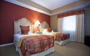 Une chambre d’hôtel avec deux lits, chacun doté d’une tête de lit, d’une table de chevet, d’une lampe et d’une fenêtre avec des rideaux.