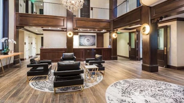 Un'ampia hall con soffitto alto, un lampadario e un'opera d'arte di grandi dimensioni appesa al muro.