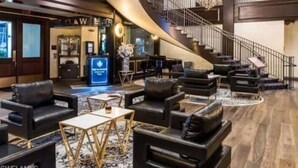 Un'ampia hall con una parete curva, diverse zone relax e una scala.