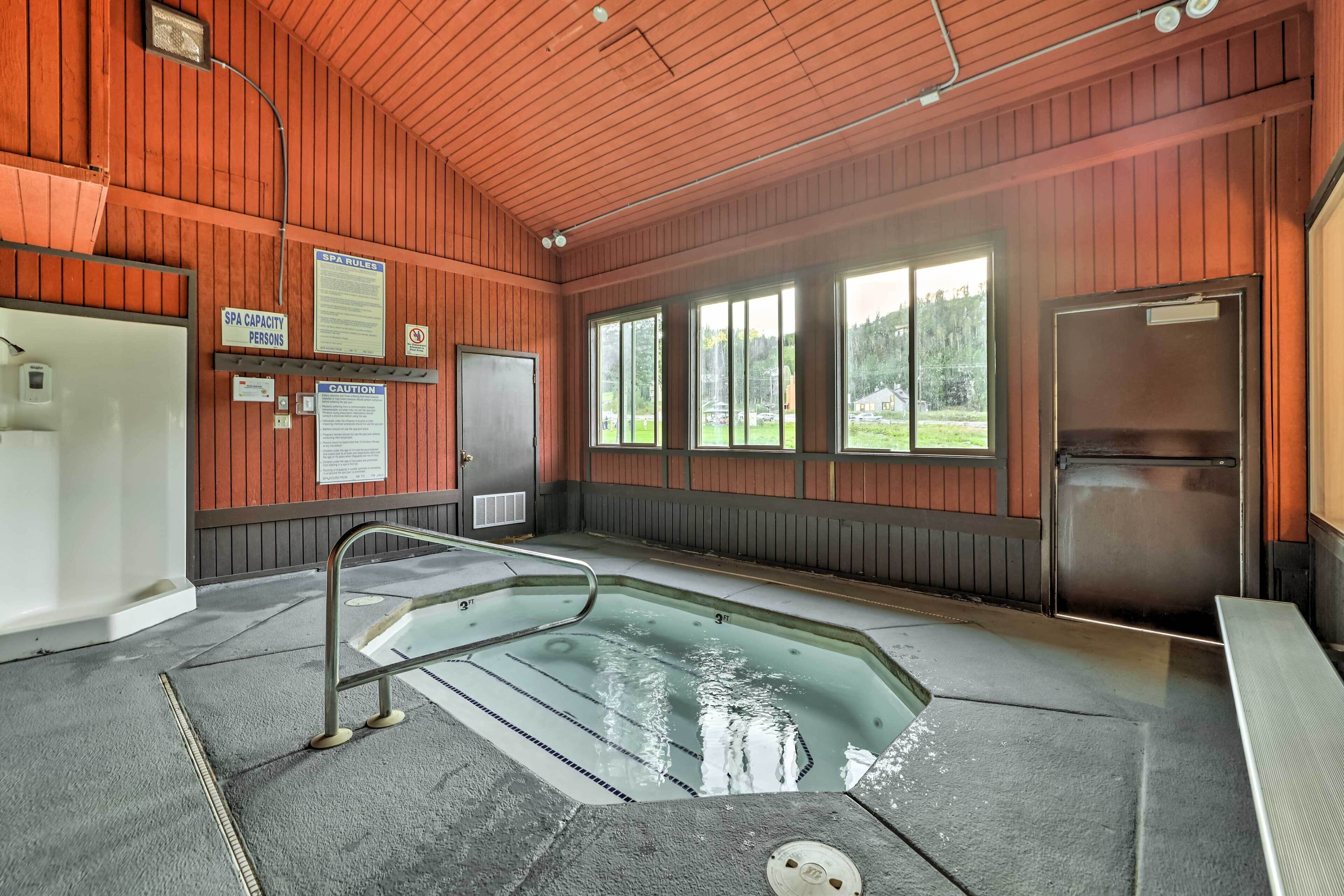 An indoor pool area with a glass viewing deck, wooden walls, and a view of the outdoors.