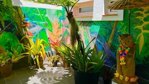 Un jardín interior vibrante con plantas en macetas y un mural colorido.