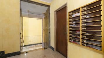 Un pasillo con una puerta cerrada, una puerta de cristal que da a una habitación y un mueble con buzones.