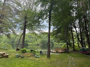 A serene lakeside campsite with picnic tables, a wooden deck, and canoe storage.