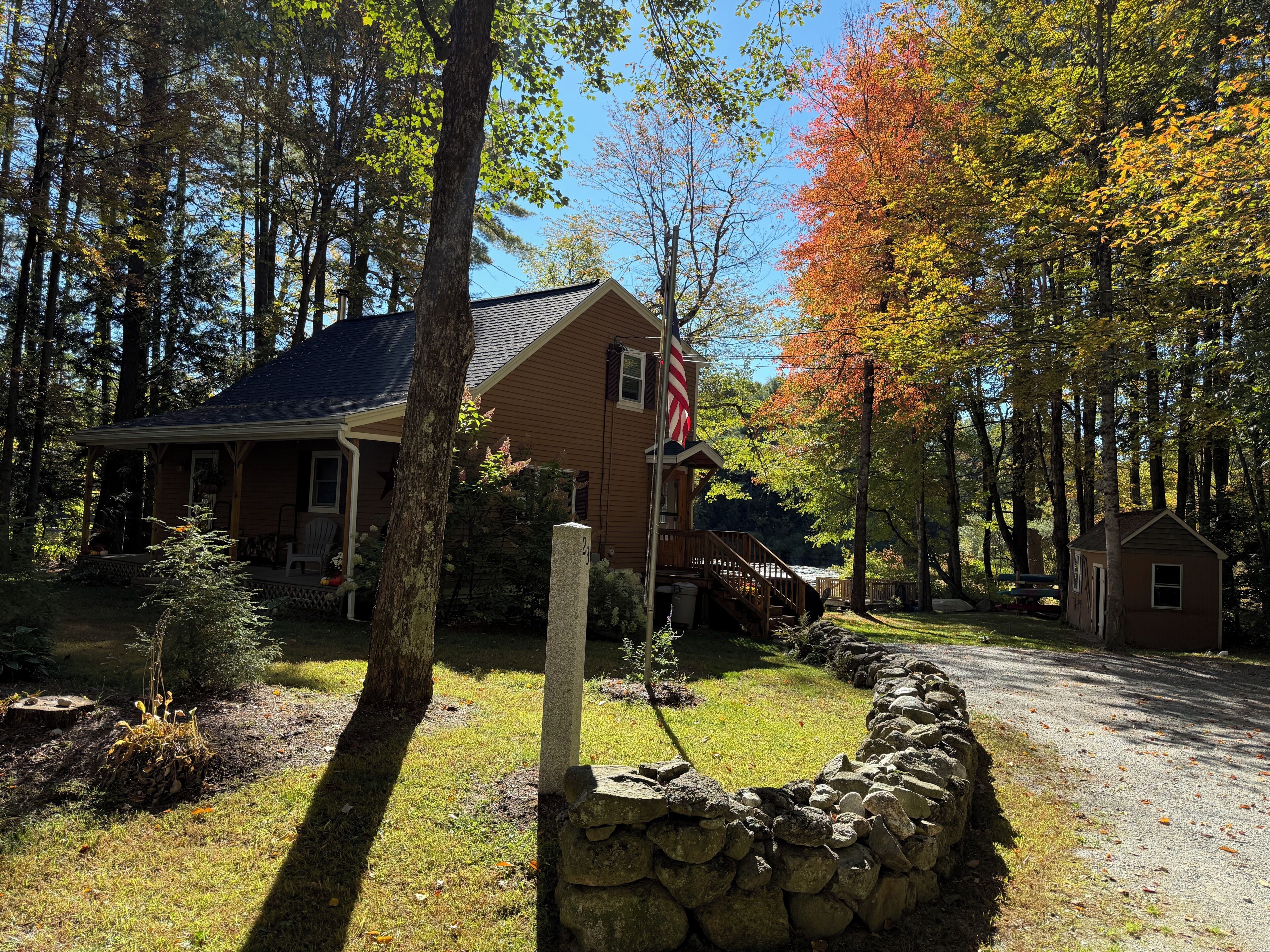 A house with a stone wall, a porch, and a flagpole.