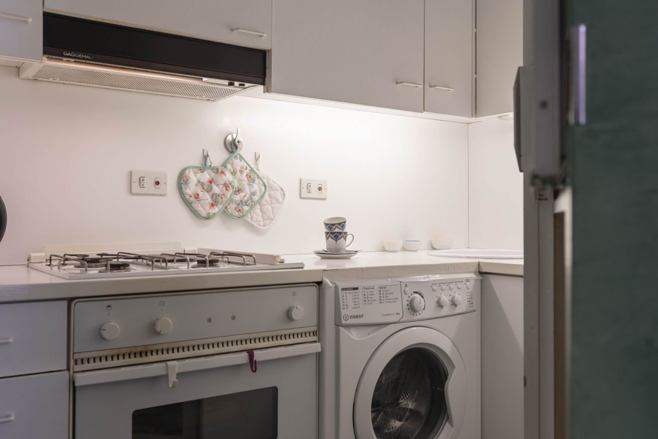 A compact kitchen with a gas stove, oven, and a front-loading washing machine.