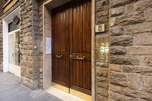Un bâtiment en pierre doté d’une porte double en bois, d’une porte en verre et d’une plaque portant le numéro « 5 ».