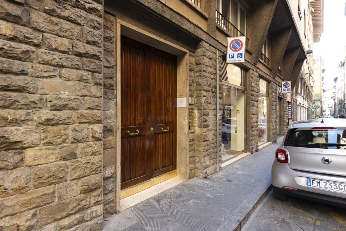 A stone building with a wooden door and a parked car.