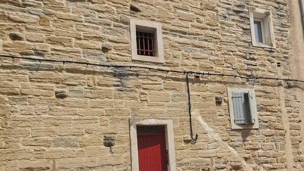 Um edifício de pedra com várias janelas e uma porta vermelha.
