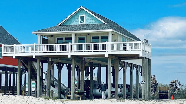 A two-story house with a balcony, wooden pillars, and a view of the beach. - Private Beachfront House on Bolivar Peninsula – Clean, Quiet & Steps to Sand (Bolivar Peninsula)