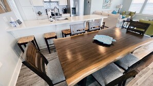 A modern kitchen with a central island, a dining area with a wooden table and chairs, and a living area with a sofa and a coffee table. - Private Beachfront House on Bolivar Peninsula – Clean, Quiet & Steps to Sand (Bolivar Peninsula)