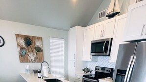A modern kitchen with a large island, white cabinets, stainless steel appliances, and wooden flooring. - Private Beachfront House on Bolivar Peninsula – Clean, Quiet & Steps to Sand (Bolivar Peninsula)