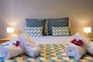 Ein Hotelzimmer mit einem Bett, zwei Kissen, zwei Nachttischlampen und zwei mit Blumen verzierten Handtüchern.