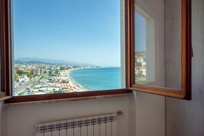 A view from a window overlooking a beach with buildings in the distance.