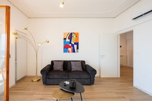 Ein modernes Wohnzimmer mit einem dunklen Sofa, einem kleinen runden Tisch und einer Stehlampe.