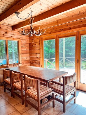 Un coin repas en bois avec une grande table et des chaises à motifs rayés et dotées de coussins.