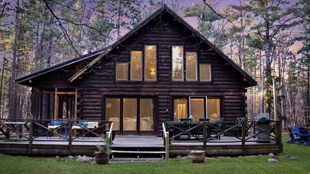 A log cabin with a deck, outdoor seating, and a fireplace. - Log Cabin w/ Hot Tub - close to Whiteface (Wilmington)