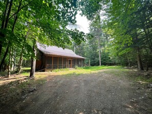 Une cabane avec un toit en métal, entourée d’une forêt dense.